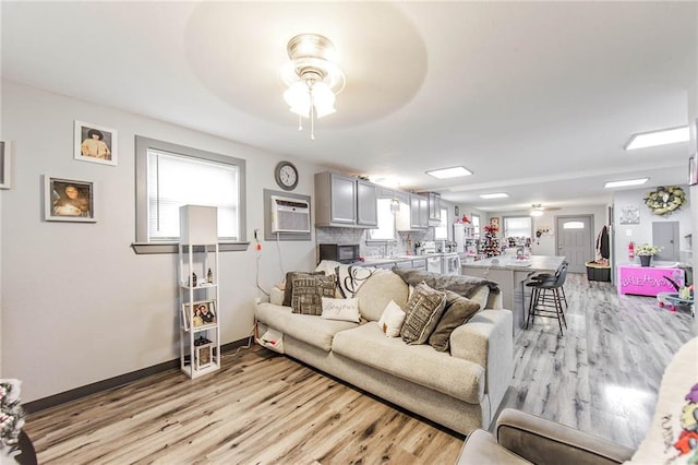 living room with light hardwood / wood-style flooring, a wall unit AC, and a wealth of natural light