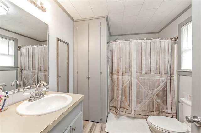 bathroom with hardwood / wood-style floors, vanity, crown molding, a shower with shower curtain, and toilet