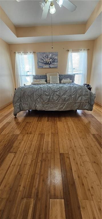 unfurnished bedroom featuring a raised ceiling, hardwood / wood-style flooring, and ceiling fan