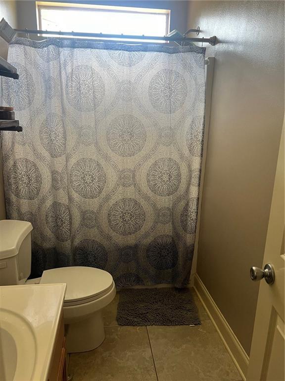 full bath with curtained shower, toilet, vanity, baseboards, and tile patterned floors