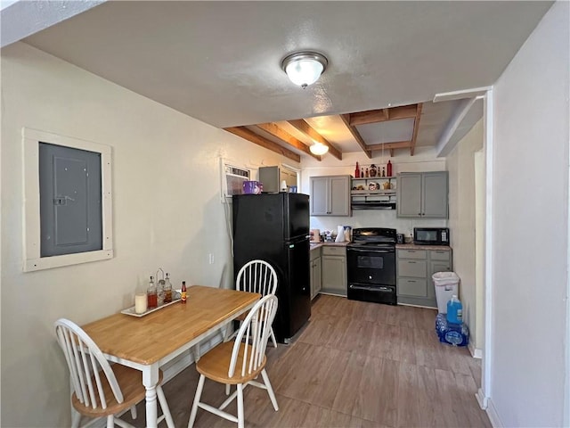 kitchen featuring ventilation hood, black appliances, gray cabinets, beamed ceiling, and electric panel