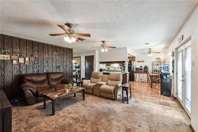 carpeted living room featuring ceiling fan and a textured ceiling