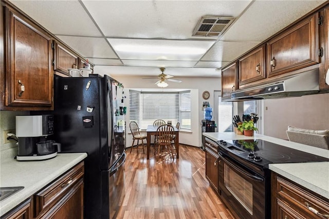 kitchen featuring a paneled ceiling, black appliances, light hardwood / wood-style flooring, ceiling fan, and dark brown cabinets