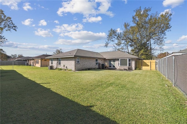 rear view of house with a yard and central AC unit