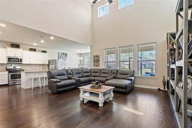 living room featuring ceiling fan, dark hardwood / wood-style flooring, and a high ceiling