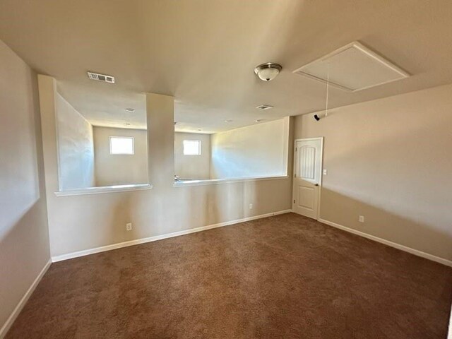 empty room with baseboards, carpet flooring, visible vents, and attic access