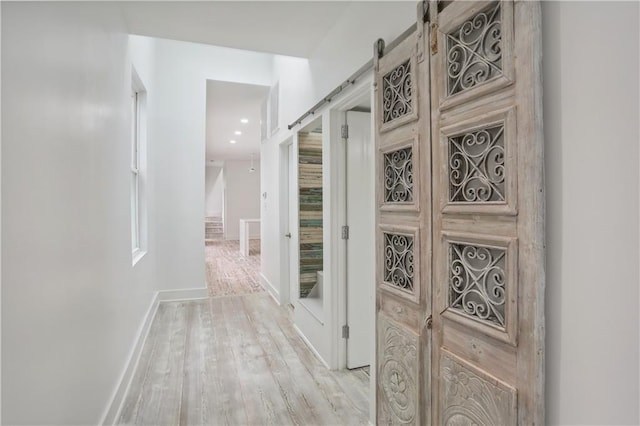 hallway featuring wood-type flooring and a barn door