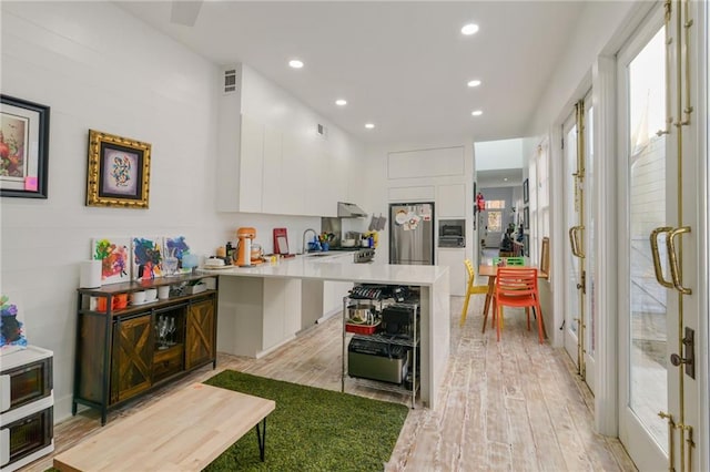 kitchen with sink, light hardwood / wood-style flooring, white cabinets, a kitchen island, and stainless steel refrigerator