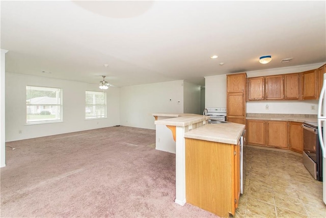 kitchen with a kitchen breakfast bar, light colored carpet, ceiling fan, sink, and a center island with sink