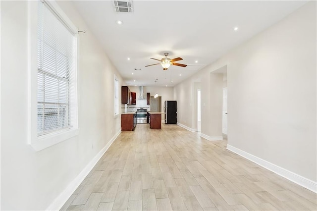 kitchen with ceiling fan, a kitchen island, black refrigerator, and light wood-type flooring