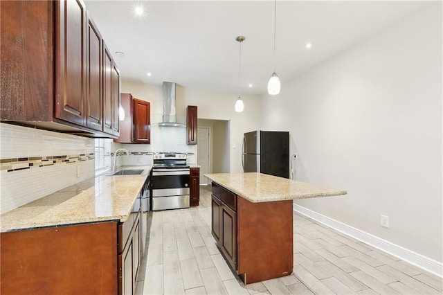 kitchen with sink, a center island, wall chimney range hood, decorative light fixtures, and appliances with stainless steel finishes