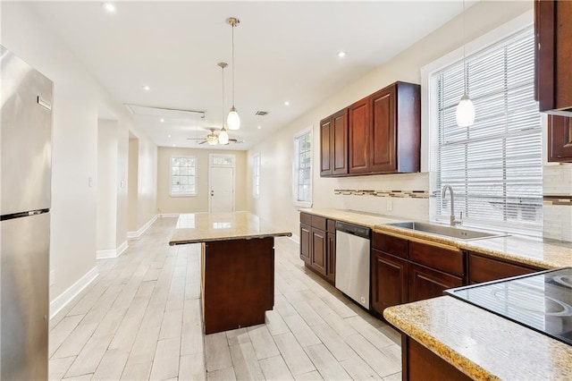 kitchen with a center island, backsplash, sink, decorative light fixtures, and stainless steel appliances