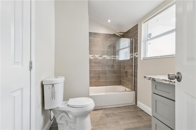 full bathroom featuring toilet, vanity, vaulted ceiling, and tiled shower / bath