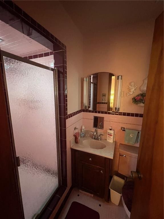 bathroom featuring vanity, a shower with shower door, and tile walls