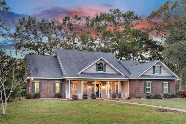 view of front of home with covered porch and a yard