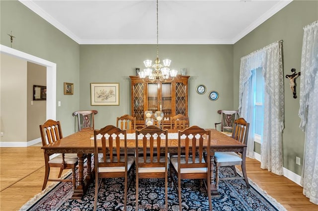 dining room featuring wood-type flooring, ornamental molding, and a notable chandelier