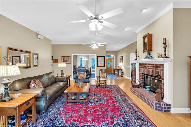 living room with a fireplace, ceiling fan, crown molding, and wood-type flooring