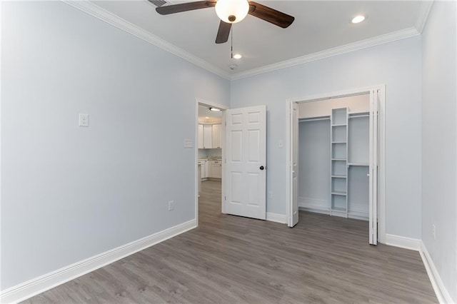 unfurnished bedroom with a closet, hardwood / wood-style flooring, ceiling fan, and crown molding