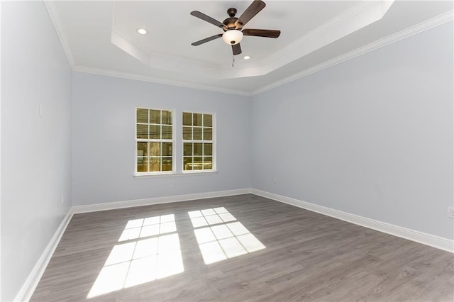 unfurnished room featuring a tray ceiling, crown molding, hardwood / wood-style floors, and ceiling fan