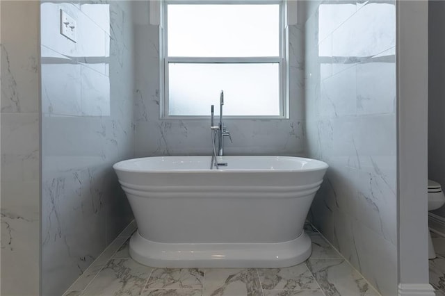 bathroom with a bath, toilet, and tile walls