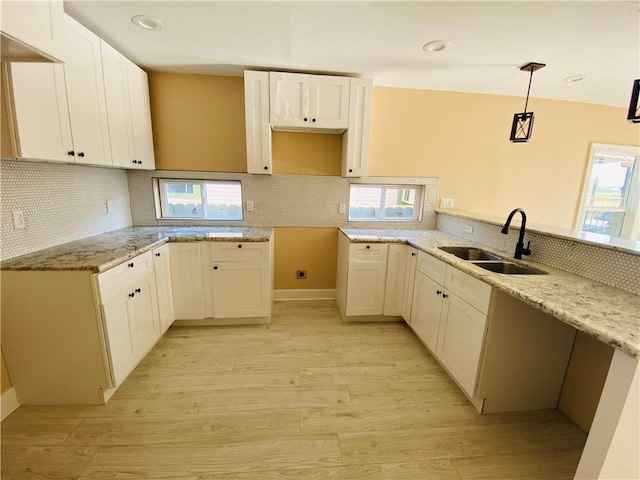 kitchen featuring pendant lighting, sink, light stone counters, and light wood-type flooring