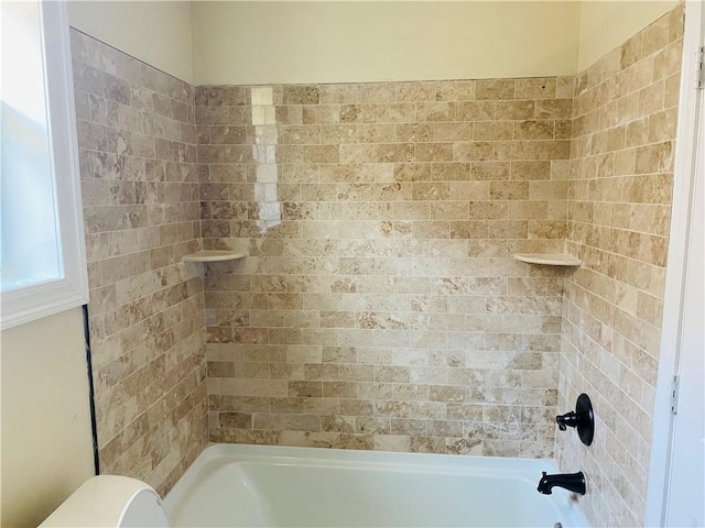 bathroom featuring toilet and tiled shower / bath combo