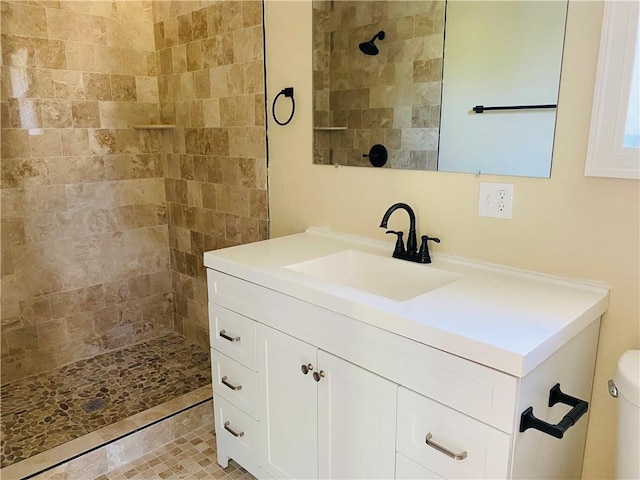 bathroom with vanity, tiled shower, and toilet