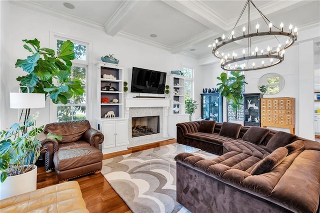 living room with crown molding, beam ceiling, hardwood / wood-style flooring, an inviting chandelier, and a premium fireplace