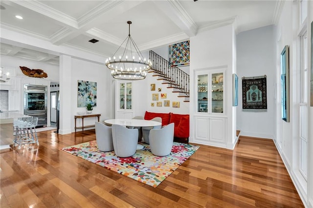 dining room featuring beamed ceiling, wood-type flooring, ornamental molding, and coffered ceiling