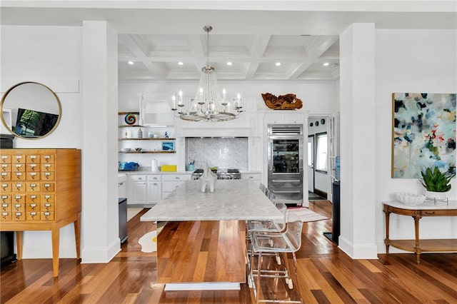 interior space with beam ceiling, coffered ceiling, and hardwood / wood-style flooring