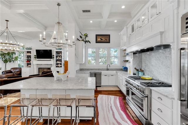 kitchen with appliances with stainless steel finishes, dark hardwood / wood-style flooring, a fireplace, beam ceiling, and white cabinets