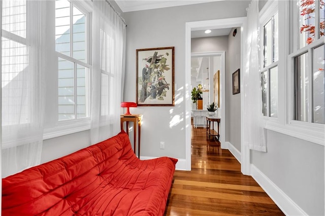 living area with wood-type flooring and crown molding