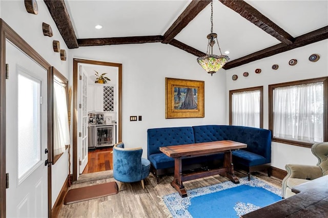 living room featuring breakfast area, lofted ceiling with beams, wood-type flooring, and wine cooler