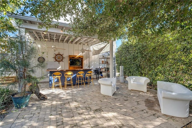 view of patio with ceiling fan and a bar