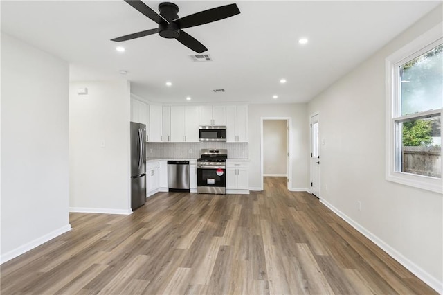 kitchen featuring white cabinetry, ceiling fan, tasteful backsplash, hardwood / wood-style floors, and appliances with stainless steel finishes