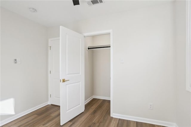 unfurnished bedroom with ceiling fan, a closet, and dark wood-type flooring