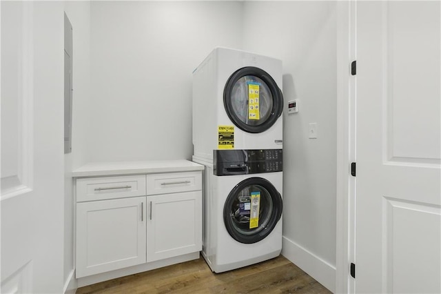 clothes washing area featuring cabinets, light hardwood / wood-style floors, and stacked washer / drying machine