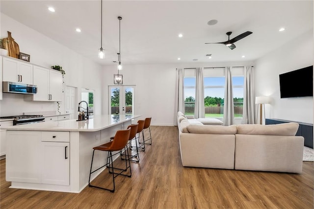 kitchen featuring appliances with stainless steel finishes, decorative light fixtures, white cabinets, and a spacious island