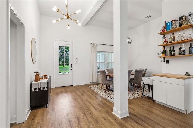 entrance foyer with an inviting chandelier, beam ceiling, and light hardwood / wood-style floors