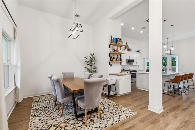 dining room featuring an inviting chandelier, a high ceiling, and light wood-type flooring