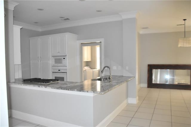 kitchen with washer and clothes dryer, white appliances, white cabinets, hanging light fixtures, and kitchen peninsula