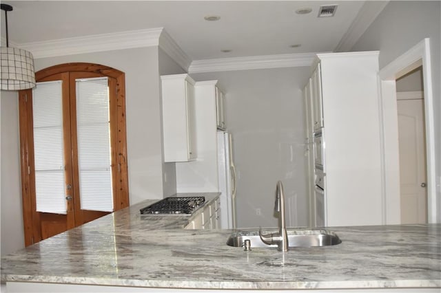 kitchen featuring light stone counters, stainless steel appliances, crown molding, sink, and white cabinetry