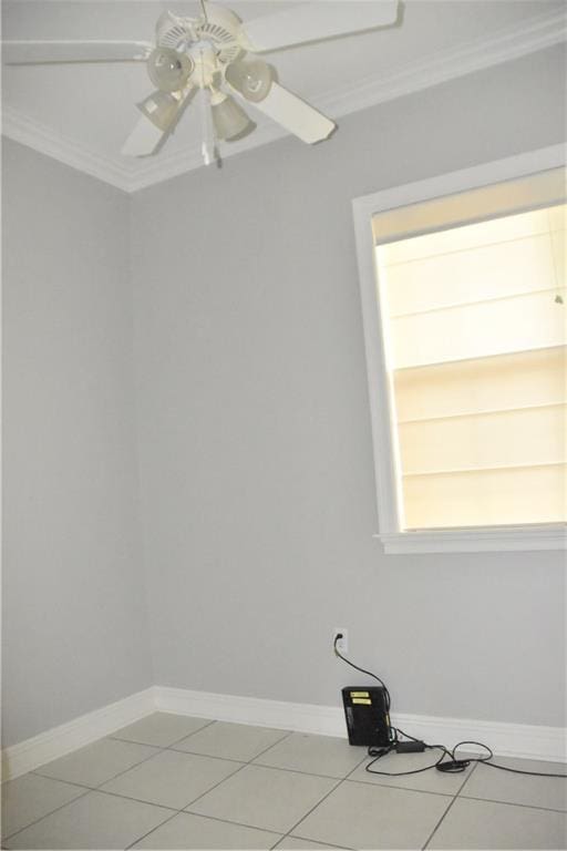 tiled empty room featuring ceiling fan and ornamental molding