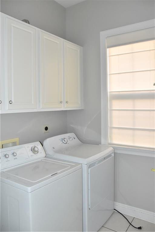 laundry room featuring cabinets, washer and clothes dryer, light tile patterned floors, and a healthy amount of sunlight