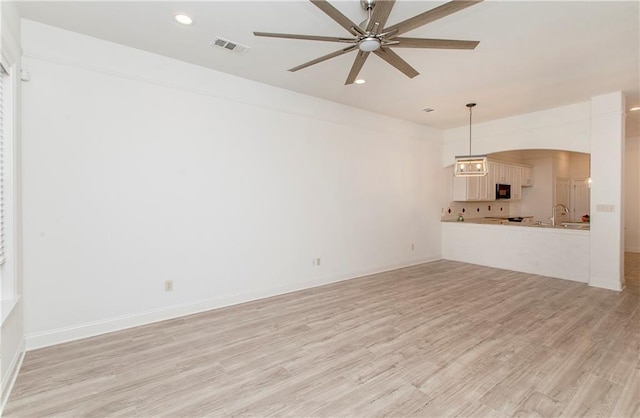 unfurnished living room featuring ceiling fan, light hardwood / wood-style flooring, and sink