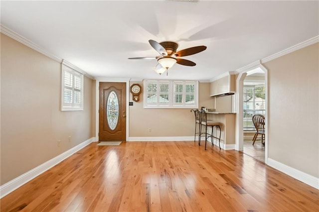 entryway featuring light wood-type flooring, ceiling fan, and crown molding