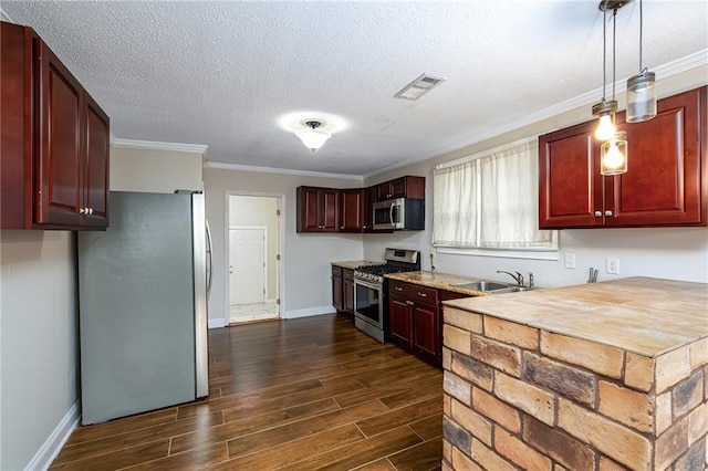 kitchen featuring appliances with stainless steel finishes, ornamental molding, dark wood-type flooring, sink, and decorative light fixtures