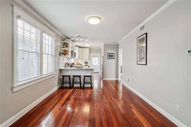 kitchen featuring crown molding, a breakfast bar, white cabinetry, dark hardwood / wood-style floors, and tasteful backsplash