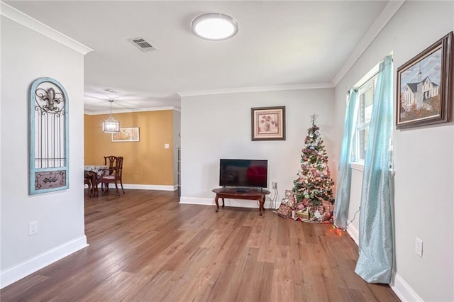 sitting room with wood-type flooring, an inviting chandelier, and crown molding