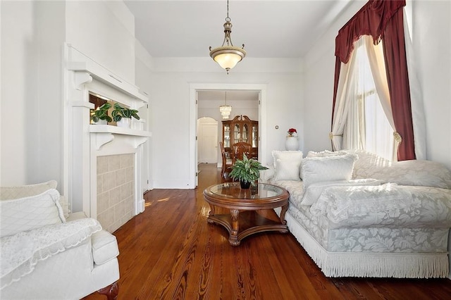 sitting room featuring a tiled fireplace and dark wood-type flooring